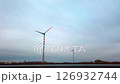 Windmills in autumn fields. Driving past modern wind mills by cloudy sky at sunset 126932744
