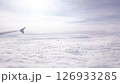 Clouds in sky. Airplane flight high up over white cloud and sunbeams at sky. Flying in clear soft clouds at sunny light day, aerial view from airplane window 126933285