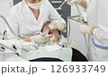 Teenager undergoes dental procedures in a bright clinic with professionals attending to oral health needs 126933749