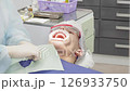 Dental professionals perform a procedure on a patient while ensuring safety and comfort in a clinical setting 126933750