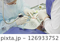 Dental professionals perform a procedure on a patient while ensuring safety and comfort in a clinical setting 126933752