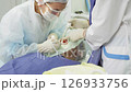 Dental professionals perform a procedure on a patient while ensuring safety and comfort in a clinical setting 126933756