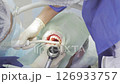 Two dental professionals perform a procedure on a patient in a clinical environment, focused and attentive to details 126933757