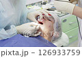 Dental professional performs cleaning procedure on a patient to remove plaque, ensuring dental health and teeth whiteness 126933759