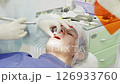 Medical professional applies ultraviolet light to cure a dental filling, ensuring proper adhesion and longevity for the patient in a clinical setting 126933760