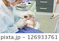 Dental professional performs cleaning procedure on a patient to remove plaque, ensuring dental health and teeth whiteness 126933761