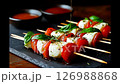 Caprese skewers with cherry tomatoes, mozzarella, and fresh basil, drizzled with balsamic glaze on a dark slate plate 126988868
