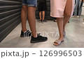 Low-angle view of customers standing in a line waiting, indoor. People in casual clothes waiting in queue. Customer waiting at store. 126996503