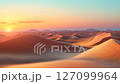 Sunset over a desert landscape with sand dunes and mountains 127099964