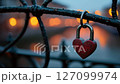 Red heart shaped padlock hanging on a fence 127099974