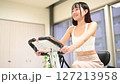 自宅の部屋でフィットネスバイクで運動する女性　家　エアロバイク　運動 127213958