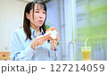 リビングで美味しそうにハンバーガーを食べる女性 127214059