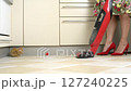 Yellow kitten is playing on the floor, getting in the way of a woman trying to vacuum 127240225