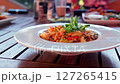 Delicious shrimp risotto served on white plate in cozy outdoor restaurant setting with fresh herbs garnish 127265415