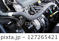 Close-up of a modern car engine compartment showcasing detailed mechanical components and wiring in daylight 127265421