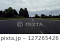 POV Low Angle View of Driving on an Open Road with Overcast Sky and Lush Greenery 127265426