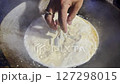 Asian cook is cooking in thai kitchen in local traditional country style, preparing traditional wok simmering thai green curry, fish balls and eggplants to cook thai food green curry popular worldwide 127298015