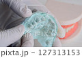 Close-up video showing gloved hands holding a dental plaster cast of a patient's upper teeth 127313153