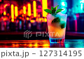 Vibrant cocktail with mint leaves and crushed ice in neon-lit nightclub. Glowing bar lights reflect on glass. Perfect for nightlife scenes, party promos, beverage ads and stylish bar visuals. 127314195