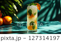 Refreshing citrus mint drink in tall glass with crushed ice. Bright orange slices and fresh mint leaves create perfect tropical summer vibe. Ideal for cocktail promos, beach bars or summer ads. 127314197