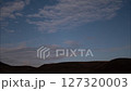 A comet in the night sky hides behind the horizon of hills 127320003