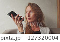 A woman in a business suit looks out the window and talks on the phone in a restaurant 127320004
