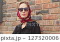 Portrait Stylish Adult young woman Caucasian in sunglasses and headscarf against brick wall 127320006
