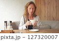 An adult young woman inhales the aroma of a drink in a cup while sitting at a table in a restaurant. The concept of relaxation and pleasure 127320007