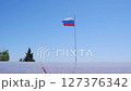 Large flag of the Russian Federation on a flagpole against a blue sky. Close up 127376342