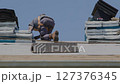 Professional Roofer Installing Asphalt Shingles on Residential House Roof Under Blue Sky 127376345