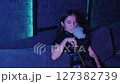 Mysterious Woman Relaxing with a Hookah in a Dark, Neon-Lit Lounge 127382739