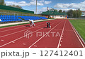 Father and daughter are running around the stadium. 127412401