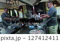 A chef prepares food in a food truck. A man is cooking in the kitchen. 127412411