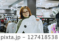 Customer choosing clothes holding white long sleeve shirt 127418538