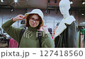 Customer trying on white bucket hat in clothing store 127418560
