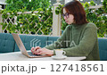 Woman freelancer working on laptop in cafe with coffee 127418561