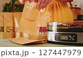 Woman putting dehydrated mushrooms in paper bag next to a dehydrator 127447979
