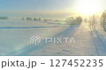 Aerial view of cold winter landscape arctic field, trees covered with frost snow, ice river and sun rays over horizon. Extreme low temperature weather. 127452235