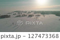 Aerial view of cold winter landscape arctic field, trees covered with frost snow, ice river and sun rays over horizon. Extreme low temperature weather. 127473368