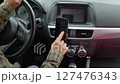 Close-up of African American female driver sitting in car, searching for travel route on smartphone using modern GPS navigation app while driving vehicle on road trip. 127476343