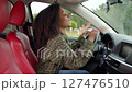 Side view of irritated attractive African American female driver stuck in traffic jam, beeping car horn, gesturing and arguing while driving vehicle in the city on busy road. 127476510