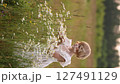 Young blonde girl in white dress picking a bouquet of daisies in a summer field. 127491129
