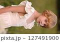 Young blonde girl in white dress picking a bouquet of daisies in a summer field. 127491900