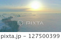Aerial view of cold winter landscape arctic field, trees covered with frost snow, ice river and sun rays over horizon. Extreme low temperature weather. 127500399