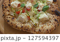 Delicious pizza variations topped with savory meat, creamy cheese, cherry tomatoes, zucchini, and fresh basil, served in a cozy local eatery. 127594397