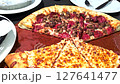 Delicious pizza featuring a combination of cheese and meat lovers toppings, served on a wooden board. The golden cheese stuffed crust and melting cheese emphasize fresh and irresistible flavors, creat 127641477