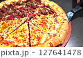 Delicious pizza featuring a combination of cheese and meat lovers toppings, served on a wooden board. The golden cheese stuffed crust and melting cheese emphasize fresh and irresistible flavors, creat 127641478