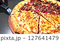 Delicious pizza featuring a combination of cheese and meat lovers toppings, served on a wooden board. The golden cheese stuffed crust and melting cheese emphasize fresh and irresistible flavors, creat 127641479