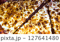 Delicious pizza featuring a combination of cheese and meat lovers toppings, served on a wooden board. The golden cheese stuffed crust and melting cheese emphasize fresh and irresistible flavors, creat 127641480