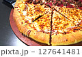 Delicious pizza featuring a combination of cheese and meat lovers toppings, served on a wooden board. The golden cheese stuffed crust and melting cheese emphasize fresh and irresistible flavors, creat 127641481